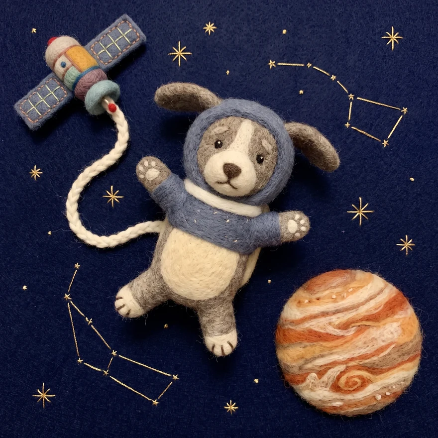 Laika floating on a tether beside a felt satellite, with a needle-felted Jupiter